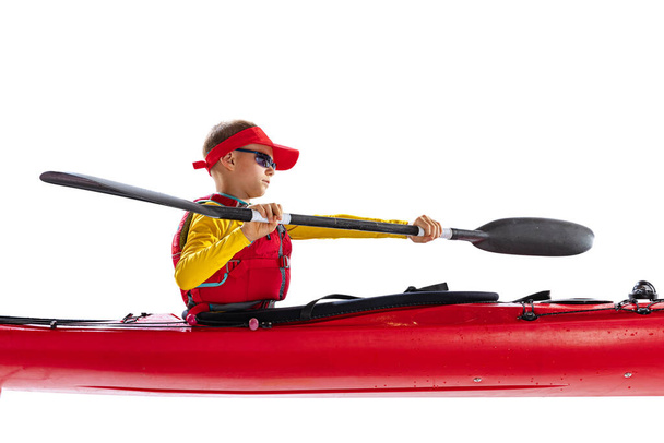 Side view. Beginner kayaker in red canoe, kayak with a life vest and a paddle isolated on white background. Concept of sport, nature, travel, active lifestyle. Copy space for ad, text, design - Φωτογραφία, εικόνα