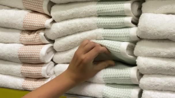 Молодой человек выбирает полотенце в супермаркете. Белые полотенца на полке - Кадры, видео