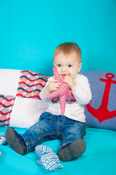 Little boy on a background of sea decor with a toy - Foto, Imagem