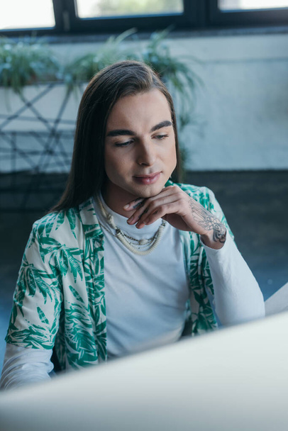 Young queer designer using blurred computer in office  - 写真・画像