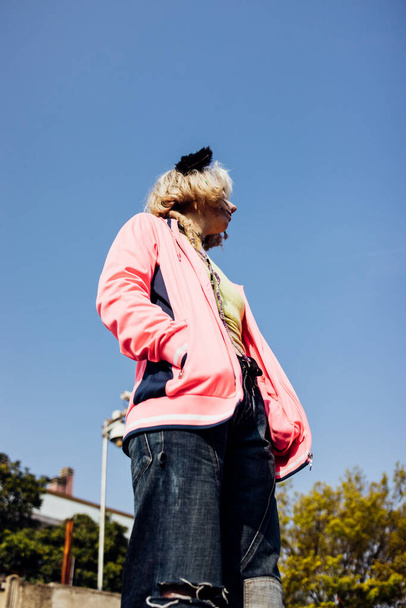 Young nonconformist rebel woman gender fluid posing outdoor looking over pensive - 写真・画像