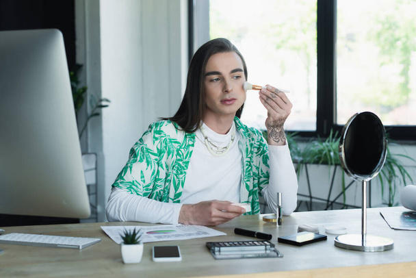 Queer designer applying makeup near devices in office  - Fotoğraf, Görsel