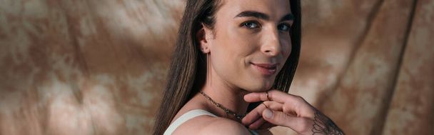 Portrait of smiling brunette queer person on abstract background, banner  - Fotografie, Obrázek