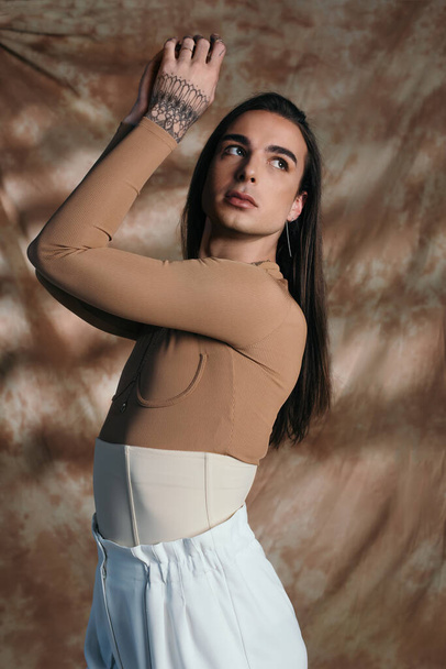 Brunette nonbinary person in corset posing on abstract brown background  - Photo, Image