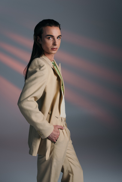 Stylish queer model in suit looking at camera on abstract background  - Φωτογραφία, εικόνα
