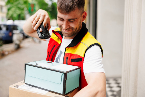 Delivery man scanning boxes a barcode packages with a handheld barcode scanner. High quality photo - Foto, afbeelding