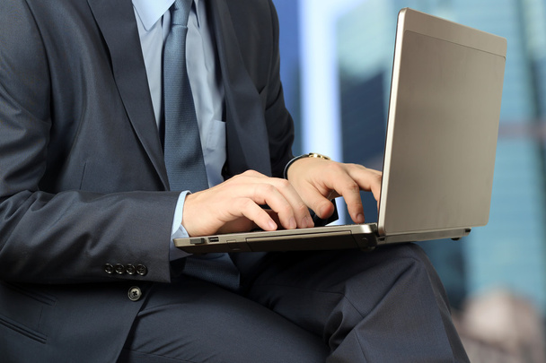 junger Geschäftsmann arbeitet mit einem Laptop, sitzt draußen, mod - Foto, Bild