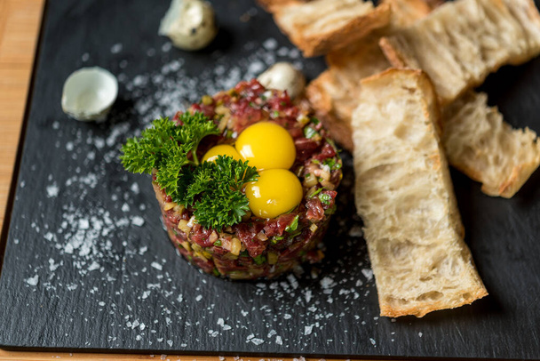 Beef tartare served with quail eggs and bread - Fotografie, Obrázek