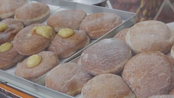 assortment of various cream-filled Berlin donuts for sale in a pastry shop - Filmati, video