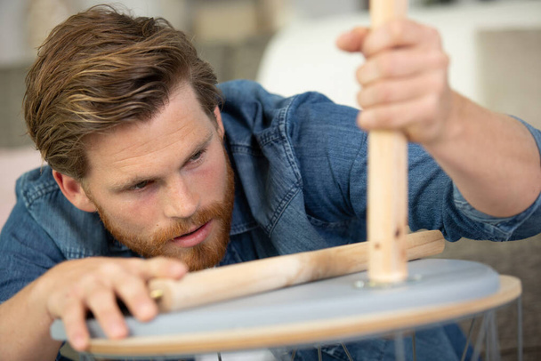 man carpenter with screwdriver in hand working in furniture repair - Фото, изображение