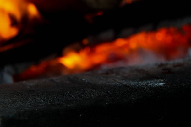 a dark stone product display surface foreground with fireplace flame in background - Фото, изображение