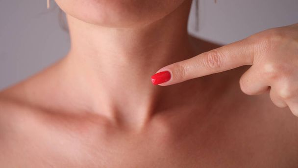 Young woman pointing her finger at neck. Thyroid disease concept - Foto, immagini