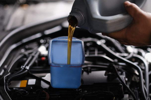 Pour gear oil into car through watering can. Replacement of technical fluids in car - Fotó, kép