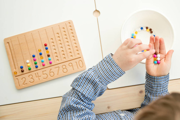 Montessori Perlen Board. Lernen, Zahlen zu zählen und zu schreiben, Kinder auf geistiges Rechnen vorzubereiten, Ordnungssinn, Konzentration, Koordination und Genauigkeit zu entwickeln. - Foto, Bild