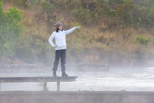 Μια γυναίκα που σκέφτεται την ομίχλη πάνω από τη λίμνη μια κρύα αυγή. Τρόπος ζωής. - Φωτογραφία, εικόνα