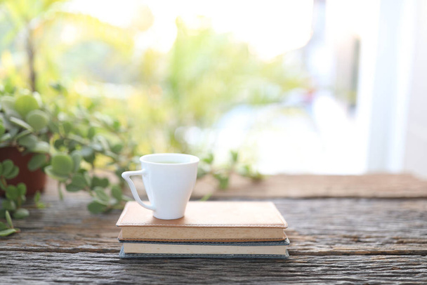 Small cup of coffee and notebooks and plant on wooden table - Fotó, kép