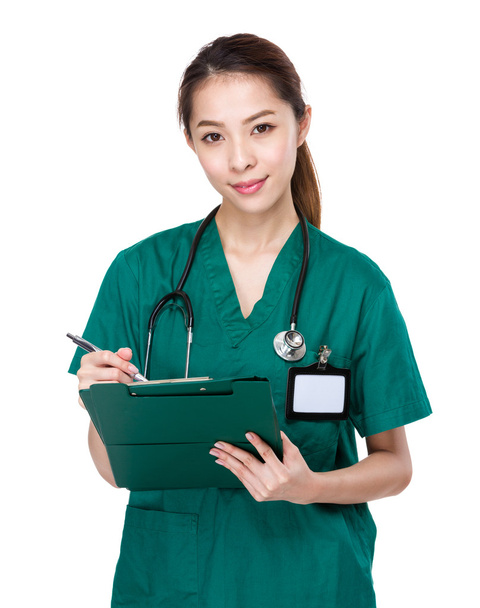 Female doctor writes on clipboard - 写真・画像