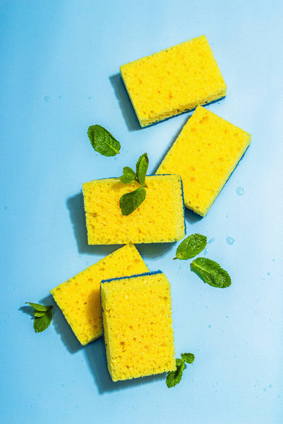Bright yellow sponges for washing dishes. Organic cleaning concept, minty freshness. A trendy hard light, dark shadow, blue background, flat lay, top view - Foto, immagini