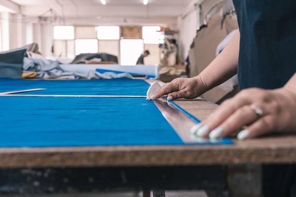 The cutter marks the fabric for cutting in the sewing workshop - 写真・画像