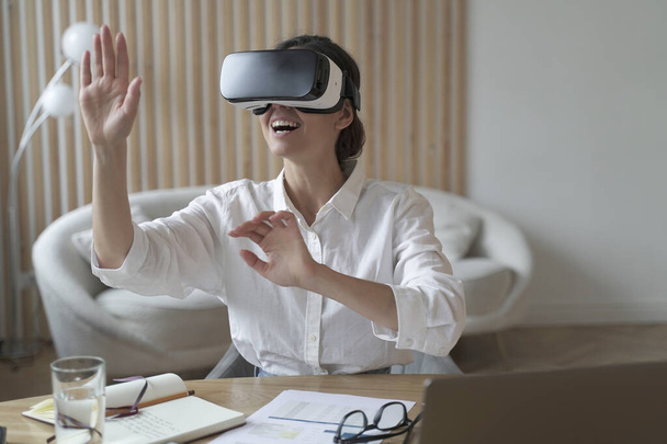 Cyberspace in business. Happy woman office worker wearing vr goggles, touching objects with hands in digital world, amazed businesswoman in 3d glasses interacting with virtual reality at work - Foto, afbeelding