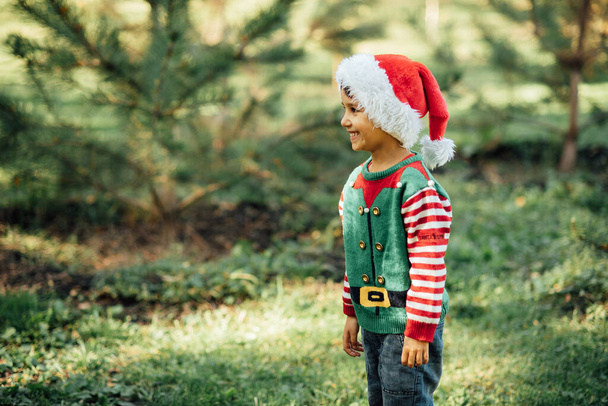 Christmas in july. Child waiting for Christmas in wood in summer. portrait of boy decorating christmas tree. winter holidays and people concept. Merry Christmas and Happy Holidays - Photo, Image