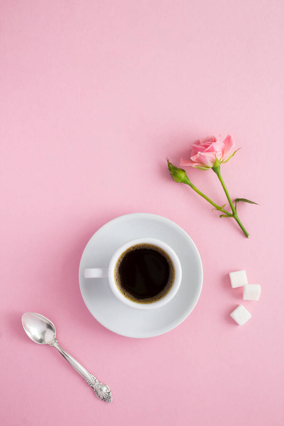 Black coffee in the white cup and pink roses on the pink  background. Top view. Location vertical. - Zdjęcie, obraz