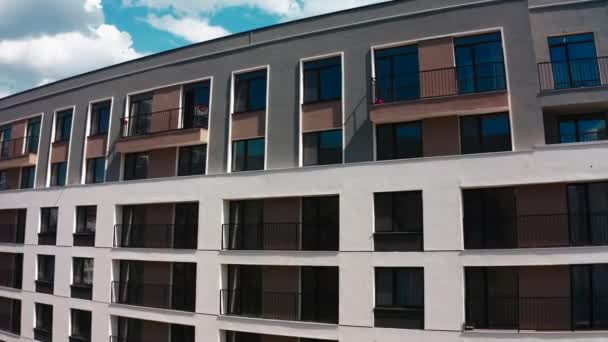 バルコニー付きのアパートメントブロック. ストック映像。 青い曇りの空の背景にあるアパートビルの空中ビュー - 映像、動画
