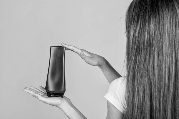 kid girl with long straight hair hold conditioner shampoo or gel bottle, hair health. - Fotografie, Obrázek