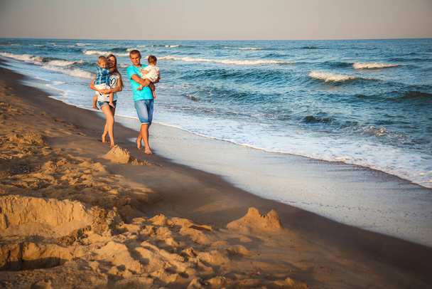 Father, mother and kids walking along the beach, near the ocean, happy lifestyle family concept. - Photo, image