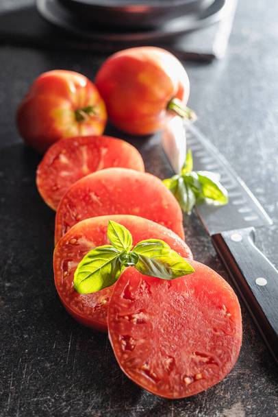 Sliced bull heart tomatoes on a black table. - Valokuva, kuva
