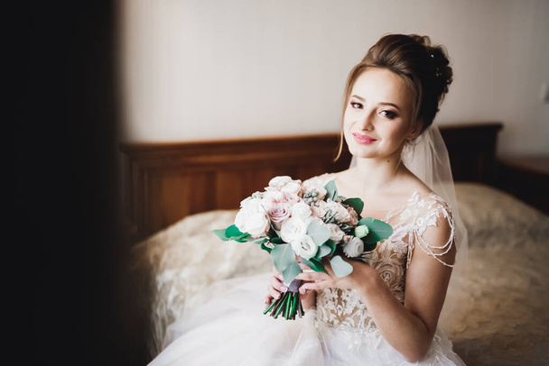 Красивая невеста в модном свадебном платье с перьями с роскошным макияжем и прической, студийная фотосессия. - Фото, изображение