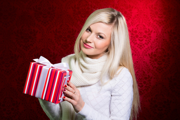 Portret van casual jonge gelukkig lachend blonde houden gestreepte geschenk  - Foto, afbeelding