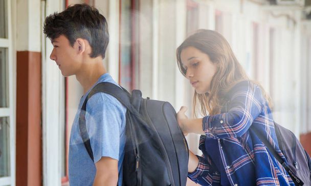 Caucásico adolescente pareja buscando en la mochila en la escuela. - Foto, Imagen