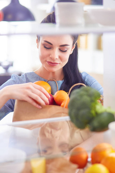冷蔵庫から新鮮な果物を取って笑顔の女性,健康食品の概念. - 写真・画像