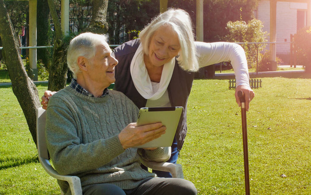Happy důchodce pár pomocí technologie gadgets venkovní na slunný den. - Fotografie, Obrázek