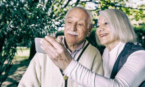 Glückliches Paar in den Siebzigern macht Selfie im Garten. - Foto, Bild