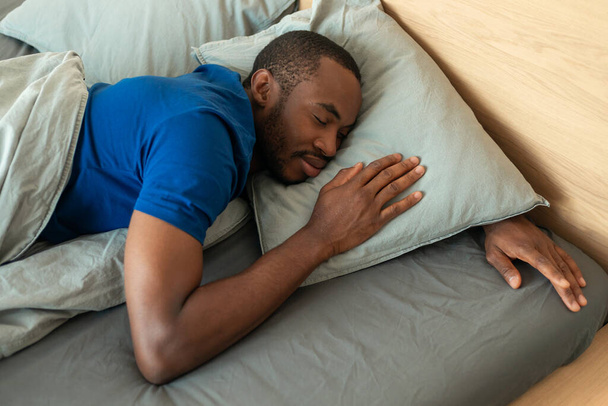 Above View Of Sleeping African American Man Lying Resting Head On Pillow In Modern Bedroom At Home. Black Guy Napping In Bed Indoor. Rest And Recreation. Selective Focus - Photo, Image