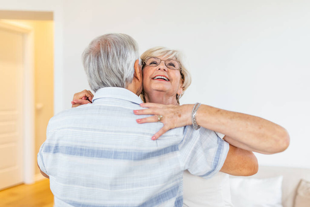 Zdjęcie głowy uśmiechnięta starsza kobieta tańcząca z mężczyzną, szczęśliwa dojrzała żona i mąż przytulający, stojąca w salonie, starsza rodzina ciesząca się chwilą czułości, świętująca rocznicę - Zdjęcie, obraz