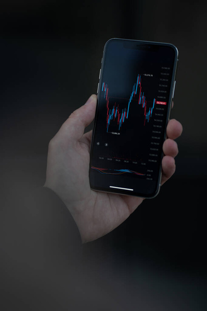 Online trading. Cropped shot of trader or investor reading financial news in real time, checking stock market data in modern mobile app on smartphone. Selective focus on screen with forex graph chart - Photo, Image