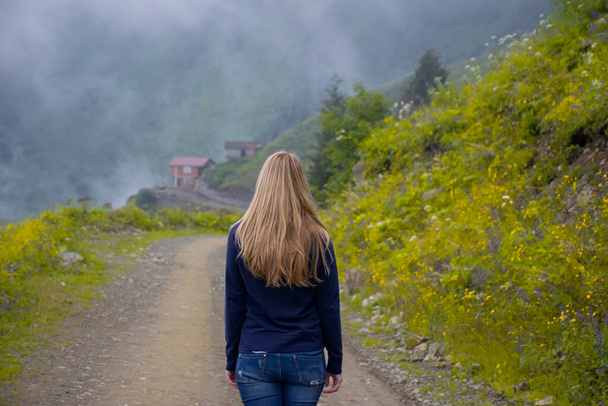 Girl walking alone on mountain highway in Spring foggy day. - Photo, Image
