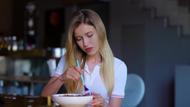 Close up portrait of pretty young blonde woman eating in restaurant alone in good mood. Caucasian joyful female having lunch or supper in cafe. Leisure. Luxury lifestyle. Slow motion. Food concept - 映像、動画