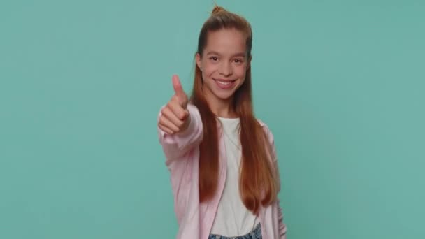 Like. Lovely pretty teenager girl raises thumbs up agrees with something or gives positive reply recommends advertisement likes good. Young stylish child kid isolated alone on blue studio background - Felvétel, videó