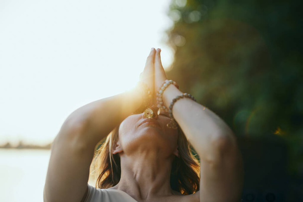 Жінка йоги тримає руки в знаковому положенні і молиться під час занять йогою на причалі біля річки в природі
. - Фото, зображення