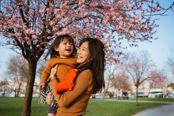 beautiful mother and daughter enjoy in the park during cherry blossom festival - 写真・画像
