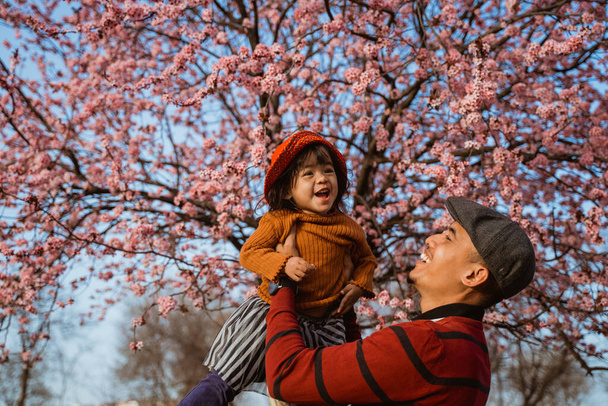 happy father and daughter looking at cherry blossom in the park - Valokuva, kuva