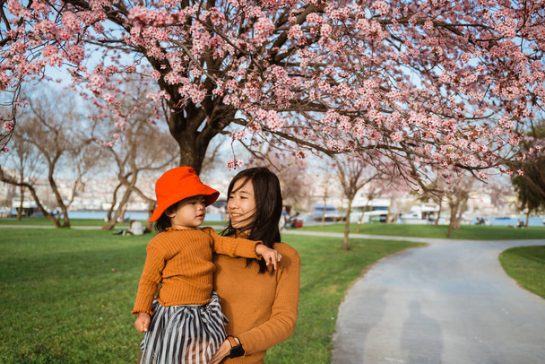 beautiful mother and daughter enjoy in the park during cherry blossom festival - Fotoğraf, Görsel