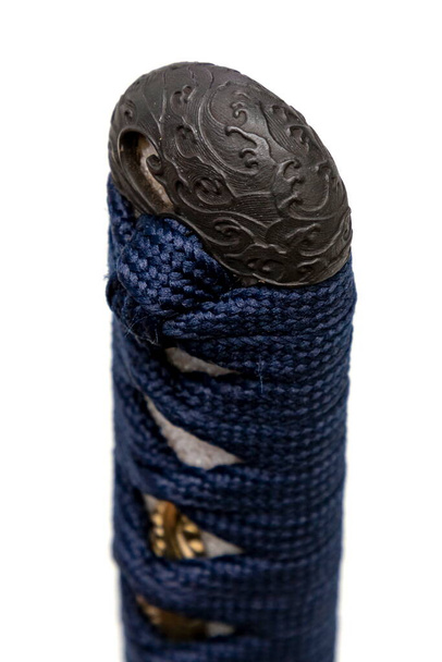 Wave design Kashira : butt cap (or pommel) made of steel on the end of the navy blue silk cord handle  Japanese sword isolated in white background. Selective focus. - Fotoğraf, Görsel