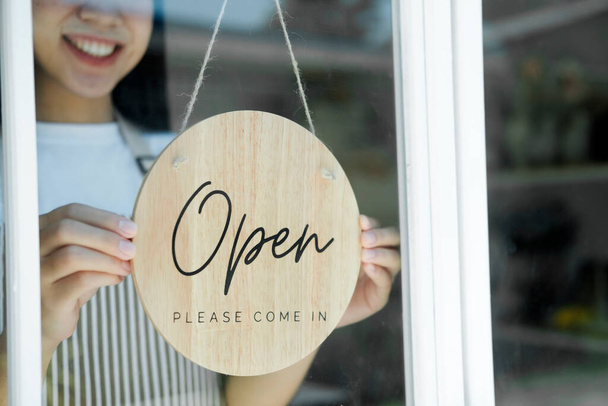 Open business owner woman wearing protection turning.open sign board on glass door in modern cafe coffee shop, cafe restaurant, retail store, small business owner, food and drink concept - Foto, imagen