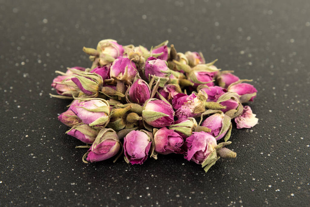 Dehydrated pink rose buds on a black cutting board - 写真・画像