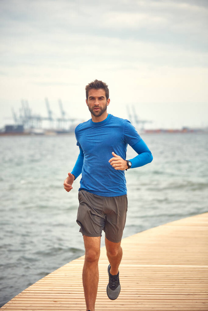 Go out and do something rewarding. a sporty middle-aged man out running by the seaside - Foto, Imagen